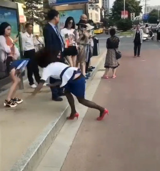 女子正得意地走着不小心摔倒了,男子扶她众人吓坏