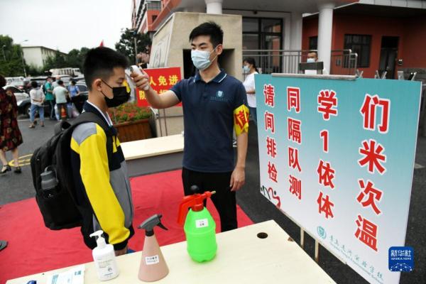 8月29日,青岛通济实验学校学生返校时在校门口间隔一米排队,测量