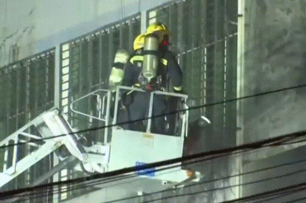 一居民家失火，有人躲到防盗窗上等待救援......