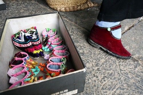 罗桂英老人脚上穿着简朴的鞋子,但她准备卖给游客的金莲鞋却十分