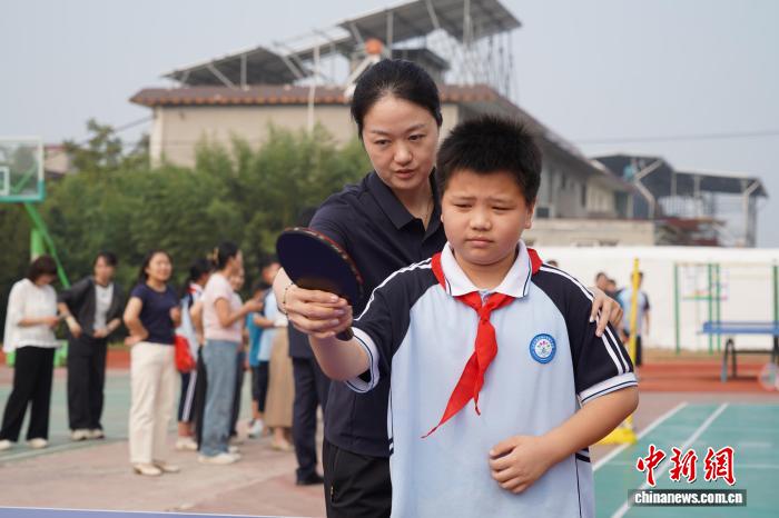 河南新乡:乒羽冠军进校园 与学生互动打球