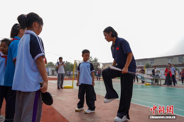 河南新乡:乒羽冠军进校园 与学生互动打球