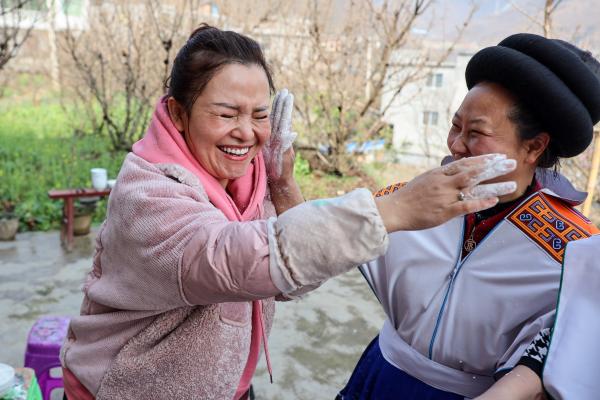 2月10日,吴穷(左)在坪子社区与苗族村民制作糍粑时嬉闹.