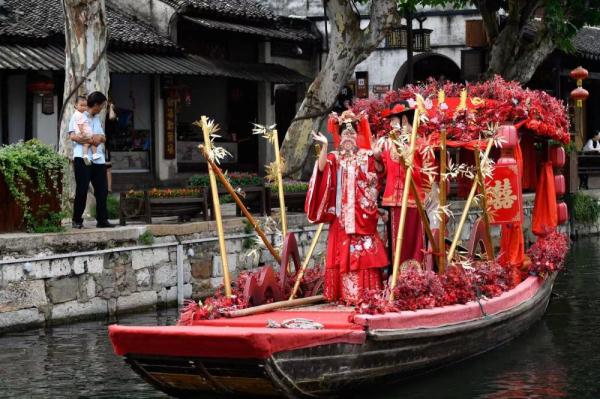 6月21日,展示湖州南潯區練市船拳的花船在南潯古鎮的河道中巡遊.