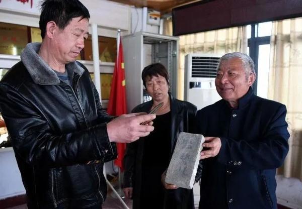 年介涛(右)向孟繁林烈士的亲属(左)展示写有孟繁林烈士名字的砖块