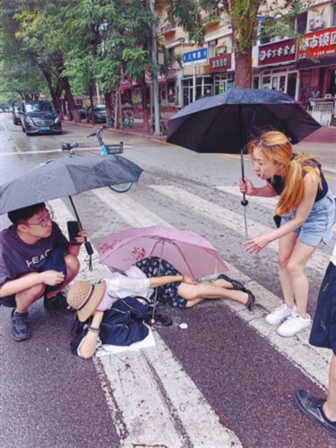 雨中一女子骑自行车摔伤 多位市民接力撑起爱心伞
