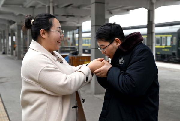 在新鄉站站臺上,杜永其給蘇媛婷哈氣暖手(2月1日攝).