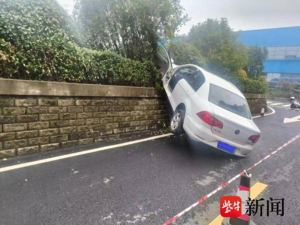 倒车时油门当成刹车，小轿车掉下停车场被悬空卡住