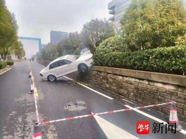 倒车时油门当成刹车，小轿车掉下停车场被悬空卡住