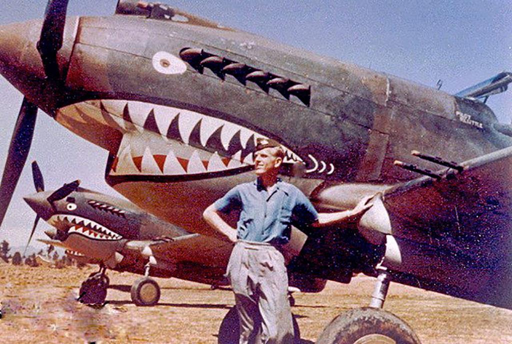 这是在二战时期的昆明巫家坝机场,一名飞虎队队员在涂装有鲨鱼嘴