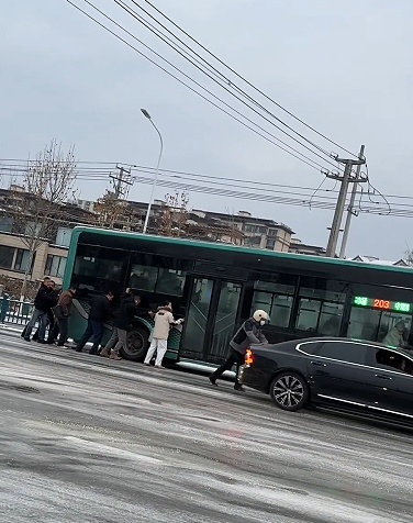 公交车雪中打滑，车上的乘客自发下车，集体推车前进
